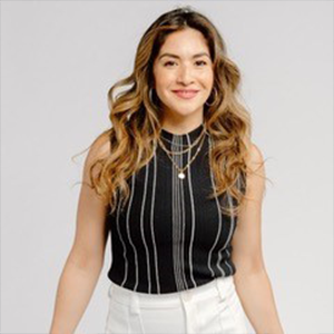 Portrait of a woman with long hair standing in front of a blank background.