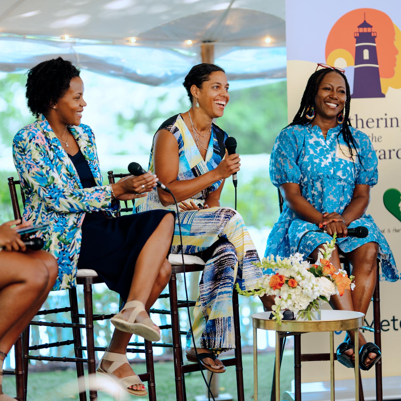 Three women speaking to an audience at a panel interview on creating economic opportunities for women of color.