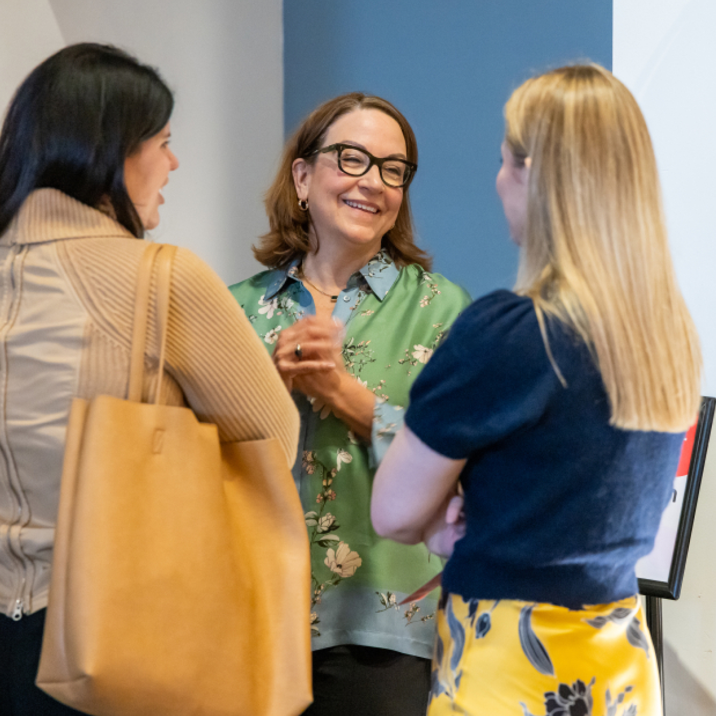 Three women standing together in conversation.