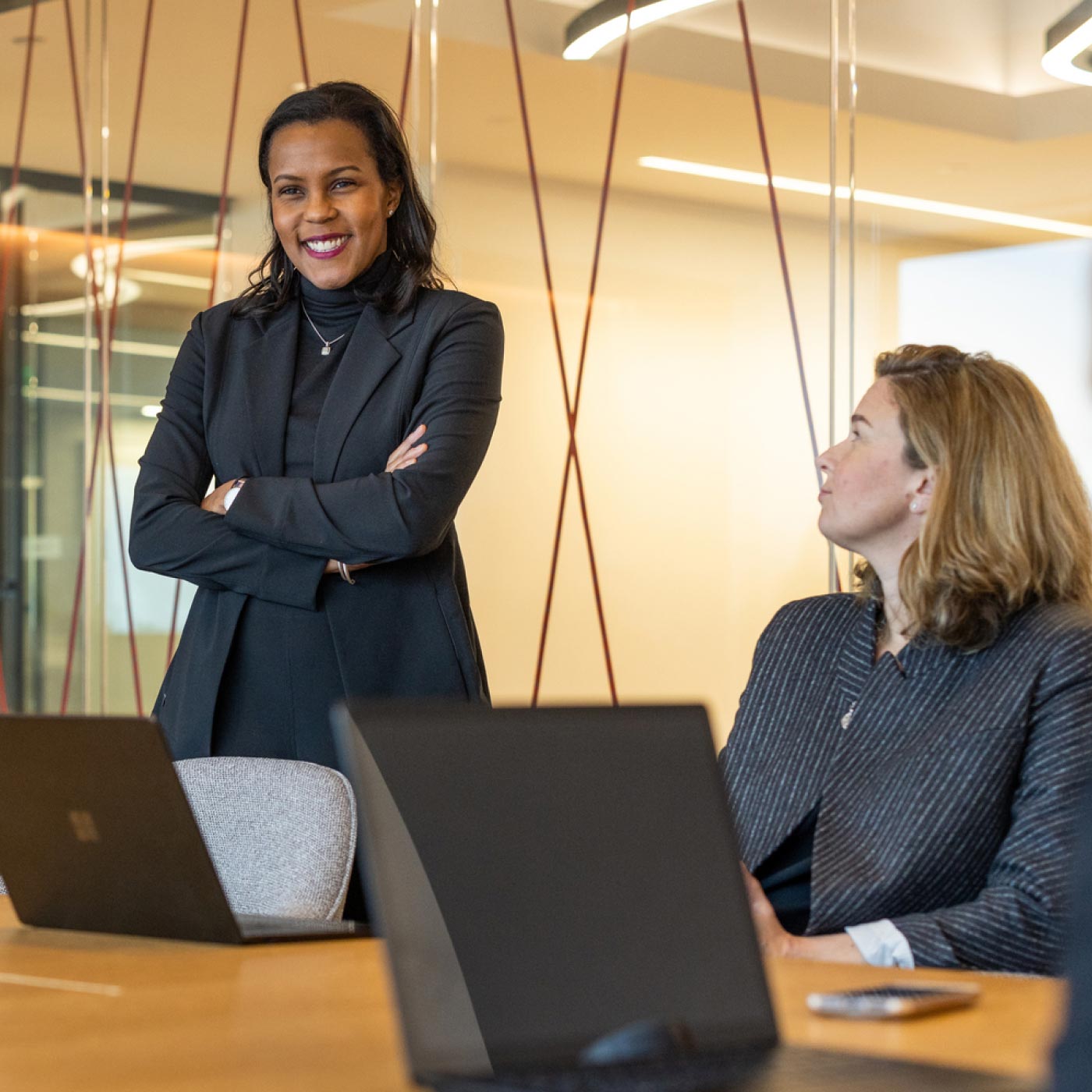 Two women in conversation in an office meeting room.