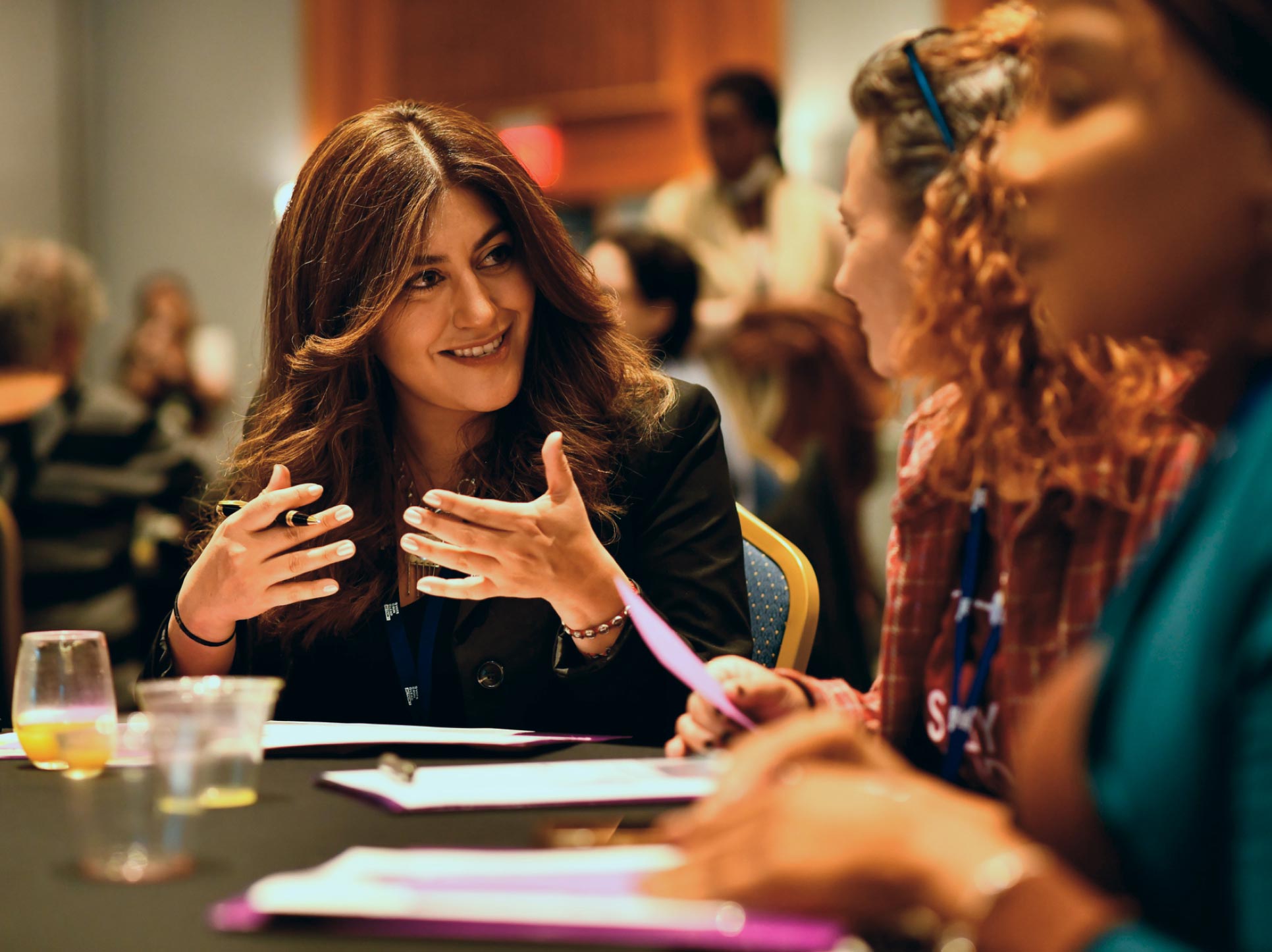 Three women collaborating together at a table during a political training summit.