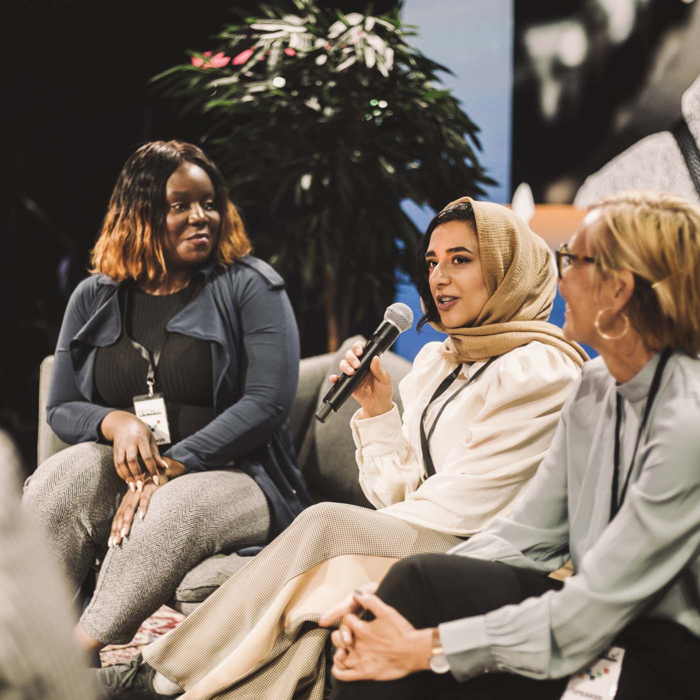 A woman speaking into a microphone on stage during a panel interview