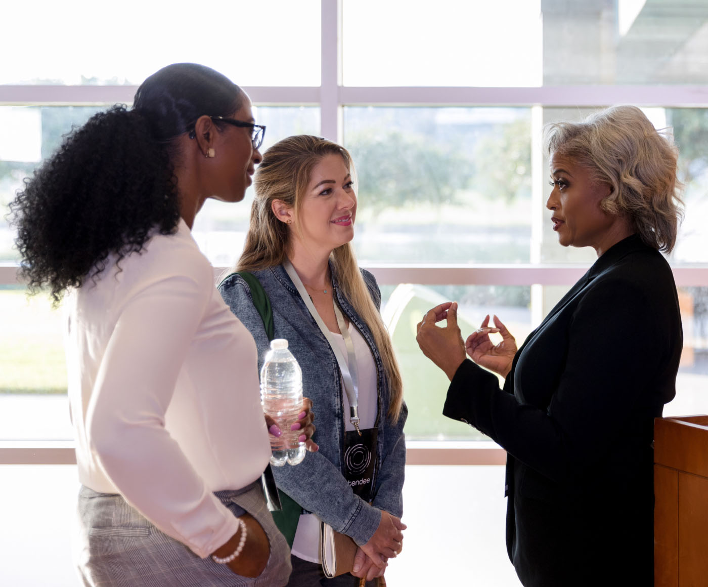 A female political candidate speaks with two people at a town hall meeting.