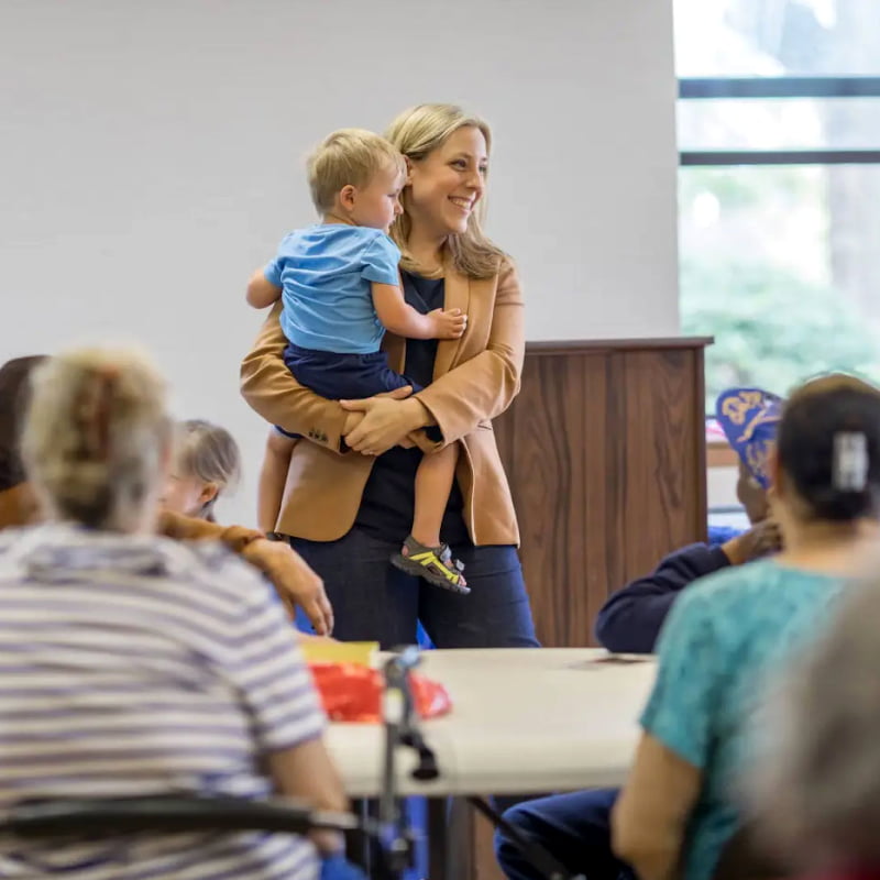 A mom holds her young son at an event to help mothers running for office.