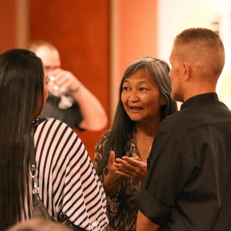 An Indigenous woman talks with a woman and a man at the Indian Pueblo Cultural Center in Albuquerque, New Mexico.