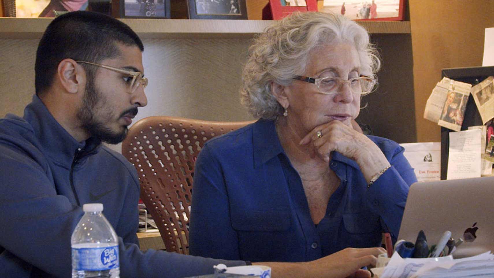 Two people look at a laptop computer.