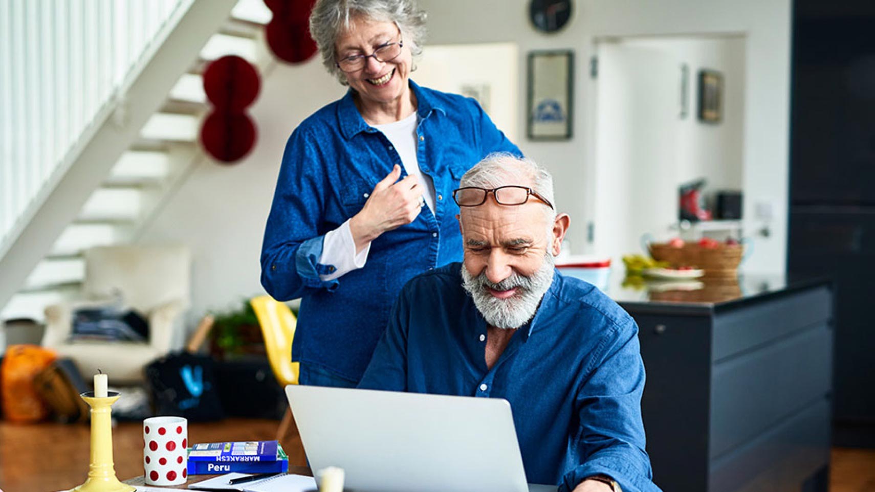 Two people smile while looking at a laptop computer.