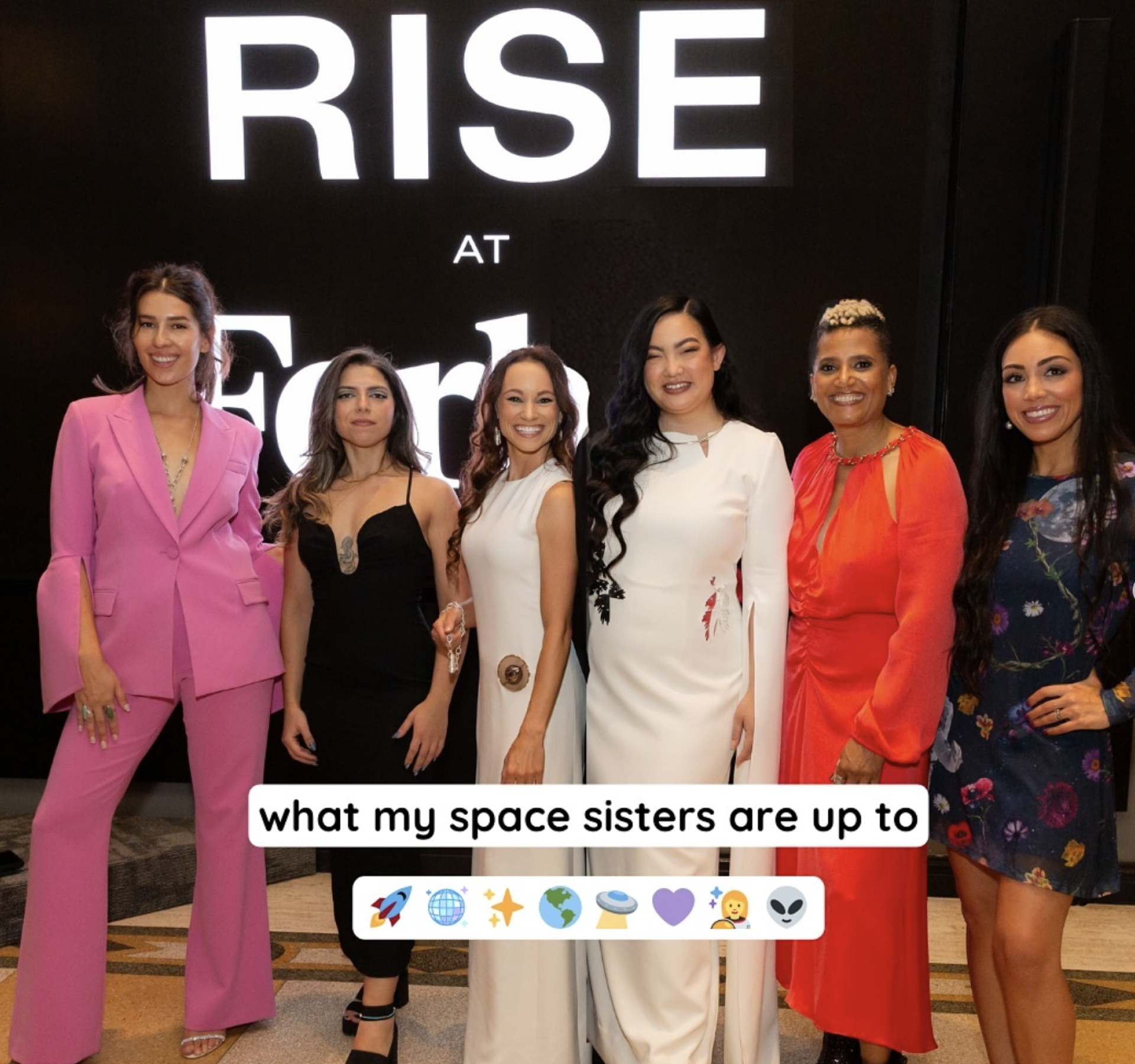 Six female astronauts taking a photo together at a professional event.