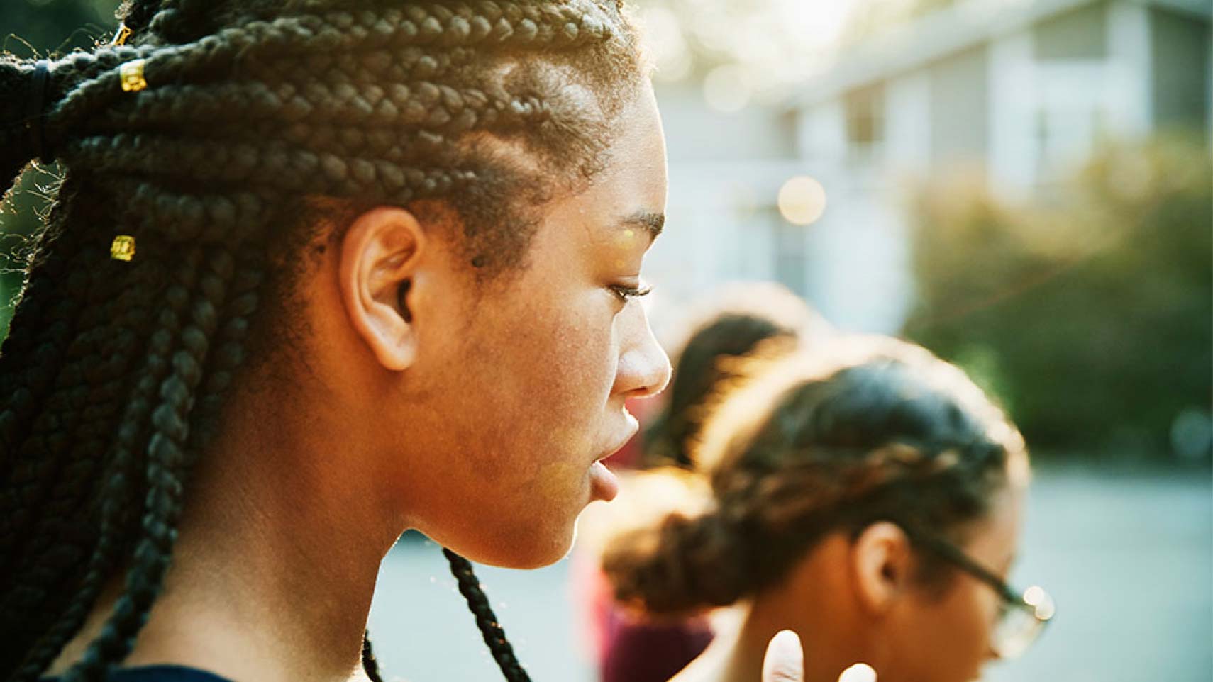 Young women who are black play outside with their friends.