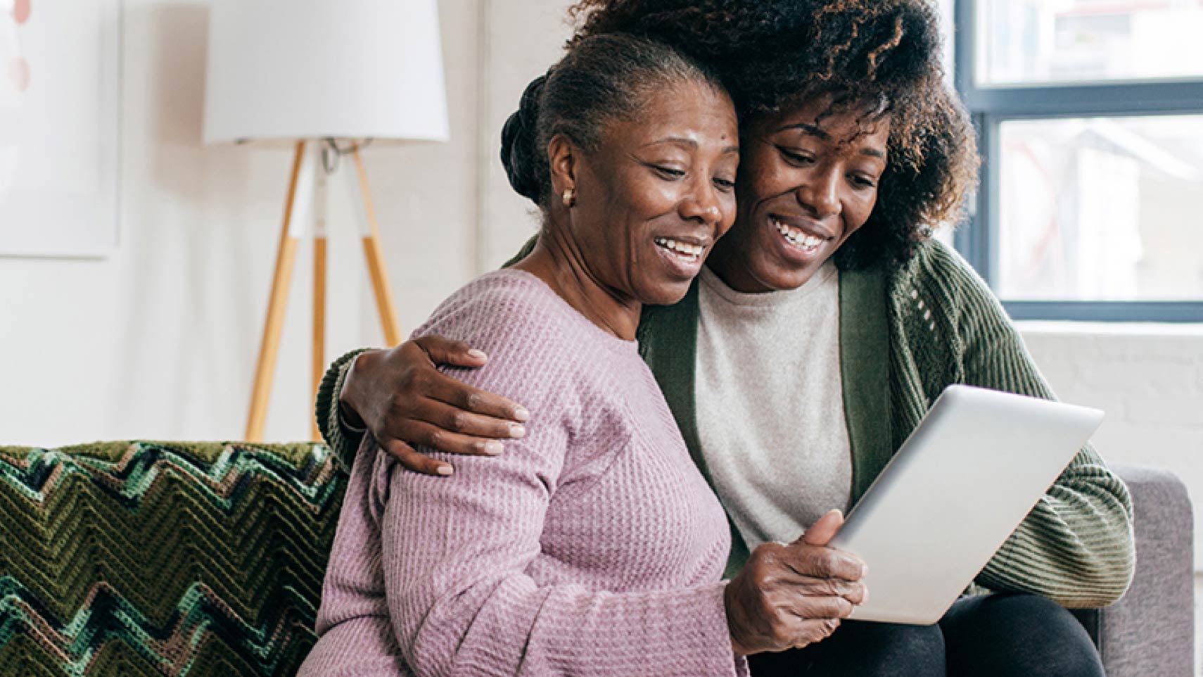Two people stand next to each other smiling into a tablet screen.