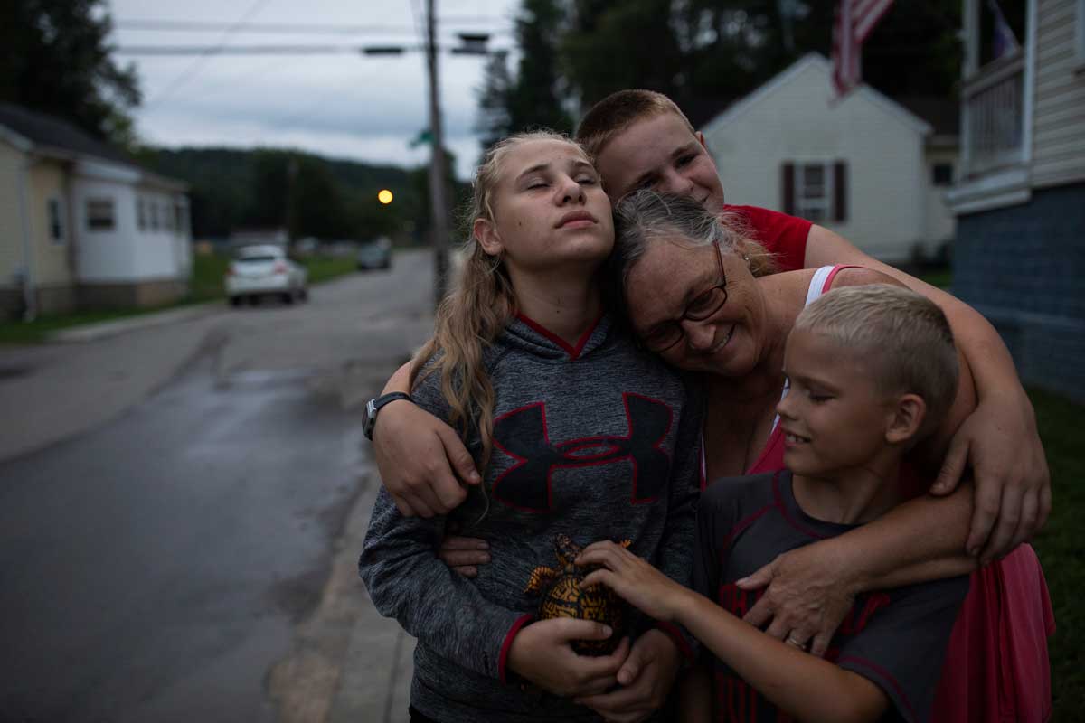 Lorrie Casto, 59, hugs her grandchildren, who just returned from exploring a park in their small coal-mining town.