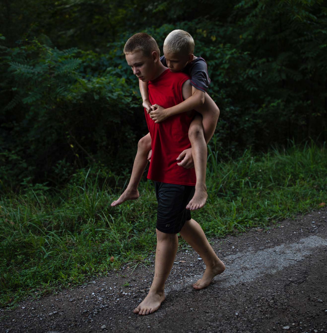 A 12-year-old boy carries his 9-year-old little brother on his back.