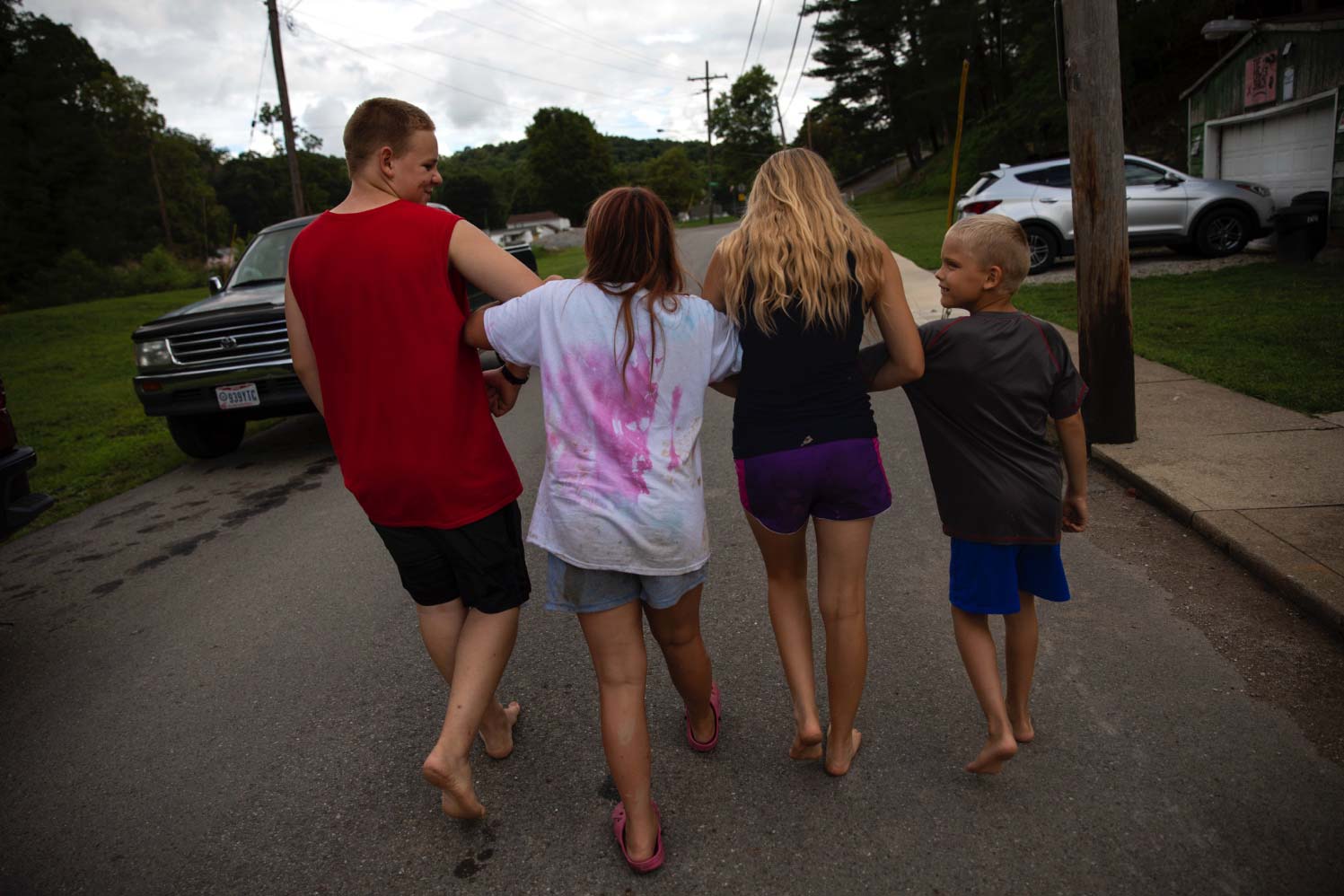 Four kids link arms and goof around in the middle of the street in the rural Ohio town where they live.