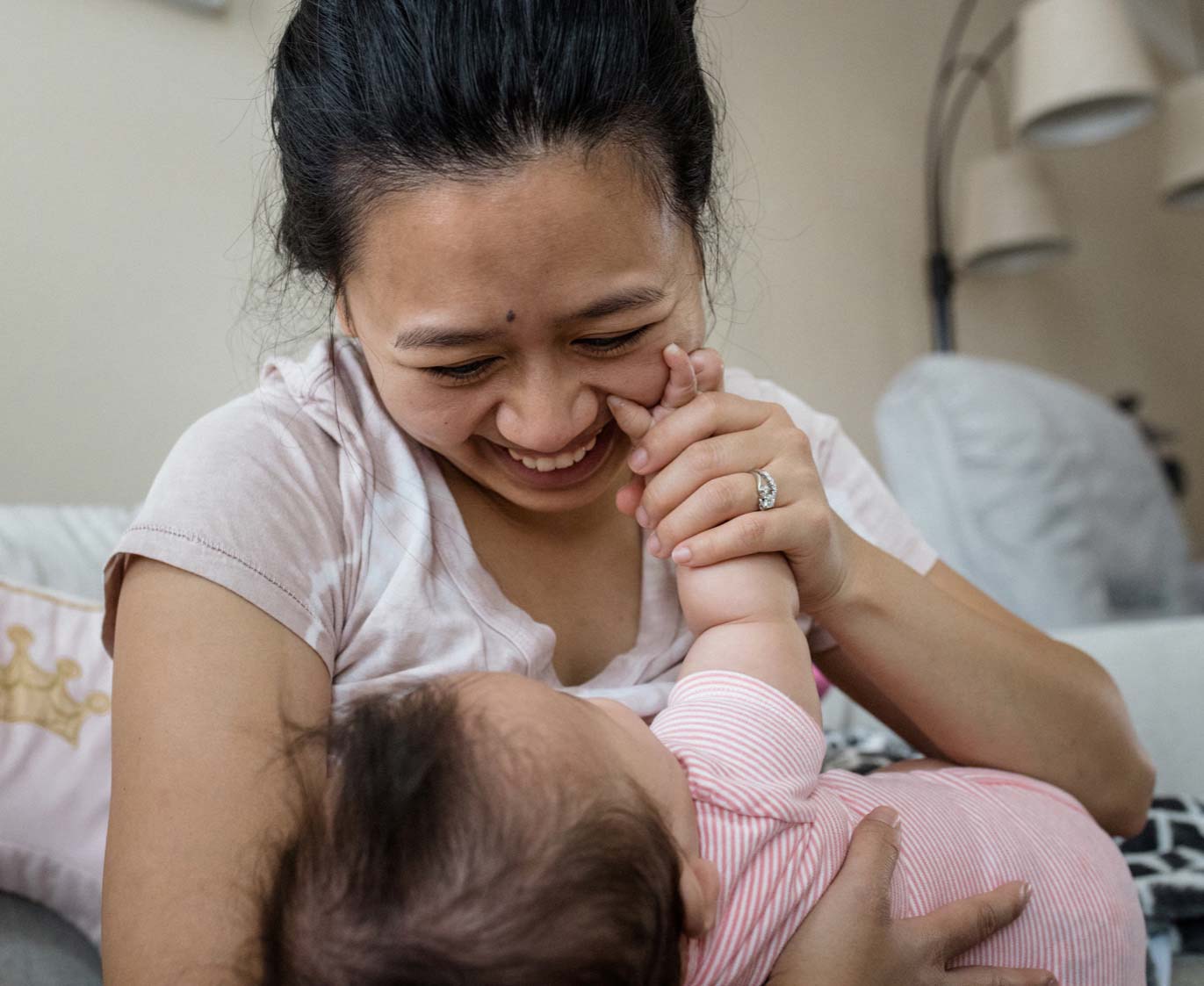 A 32-year-old woman beams at her baby, who reaches up to touch her mother's face.