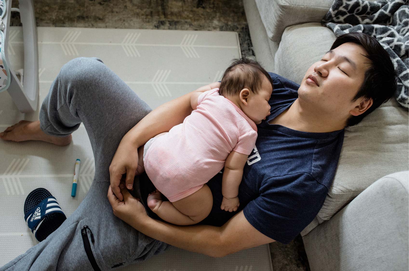 A 35-year-old man naps with his 4-month-old daughter in his arms.