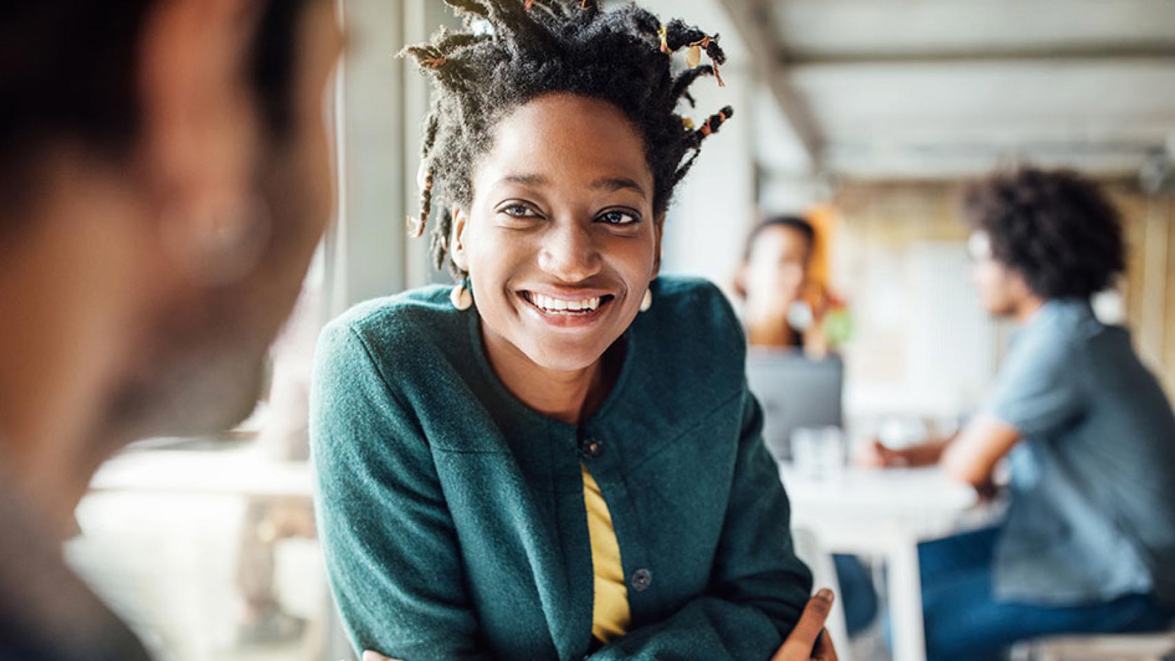 A person looks at someone else and smiles while other people sit in the background.