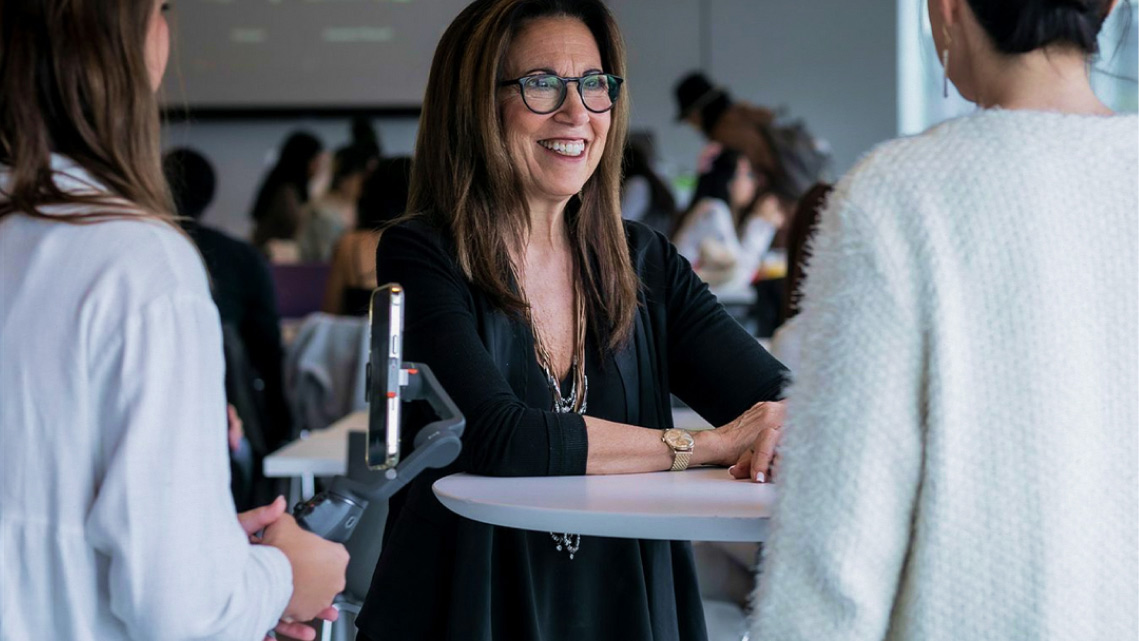 Dr. Judith Spitz speaks with students at a table during an event.