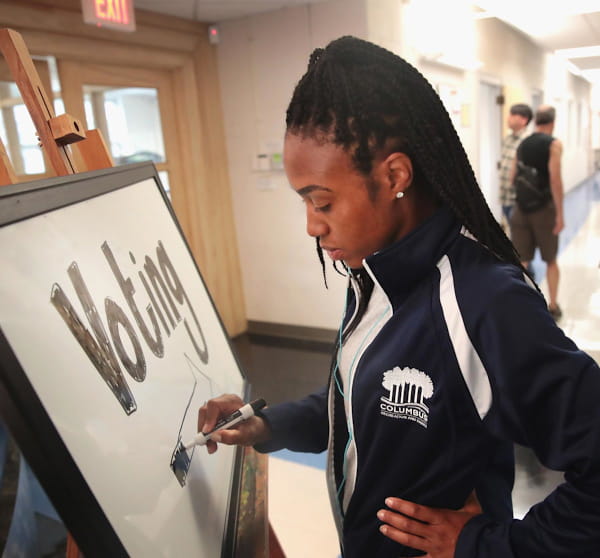 A woman makes a sign to direct voters at a polling place.