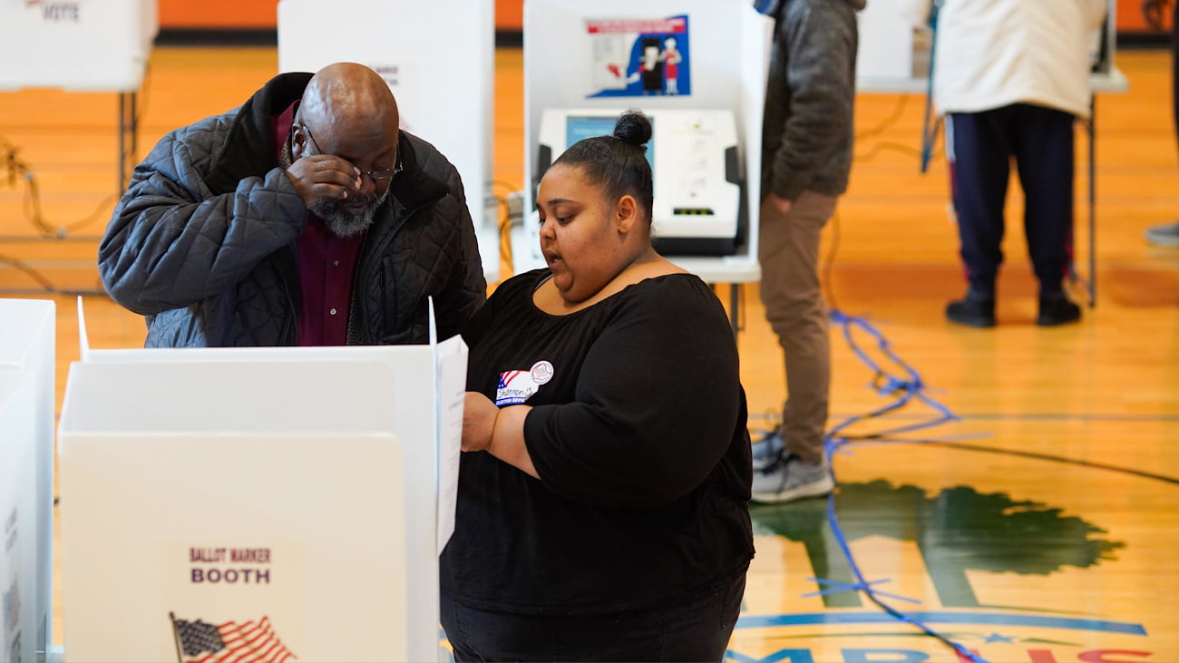 A poll worker helps a voter.
