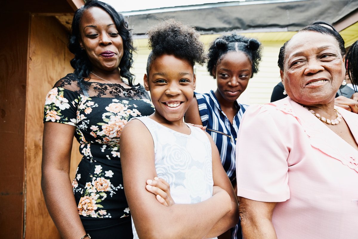 Portrait of smiling granddaughters standing with mother and grandmother.