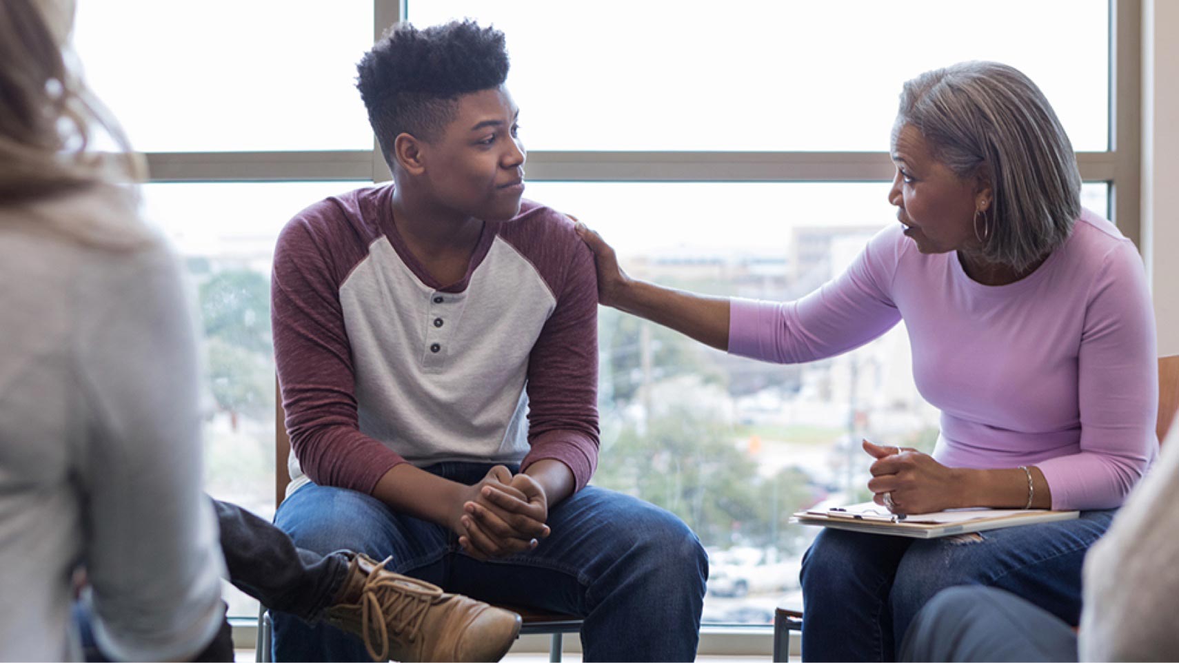 A small group of people sits together, and one person puts their arm on another person's shoulder.
