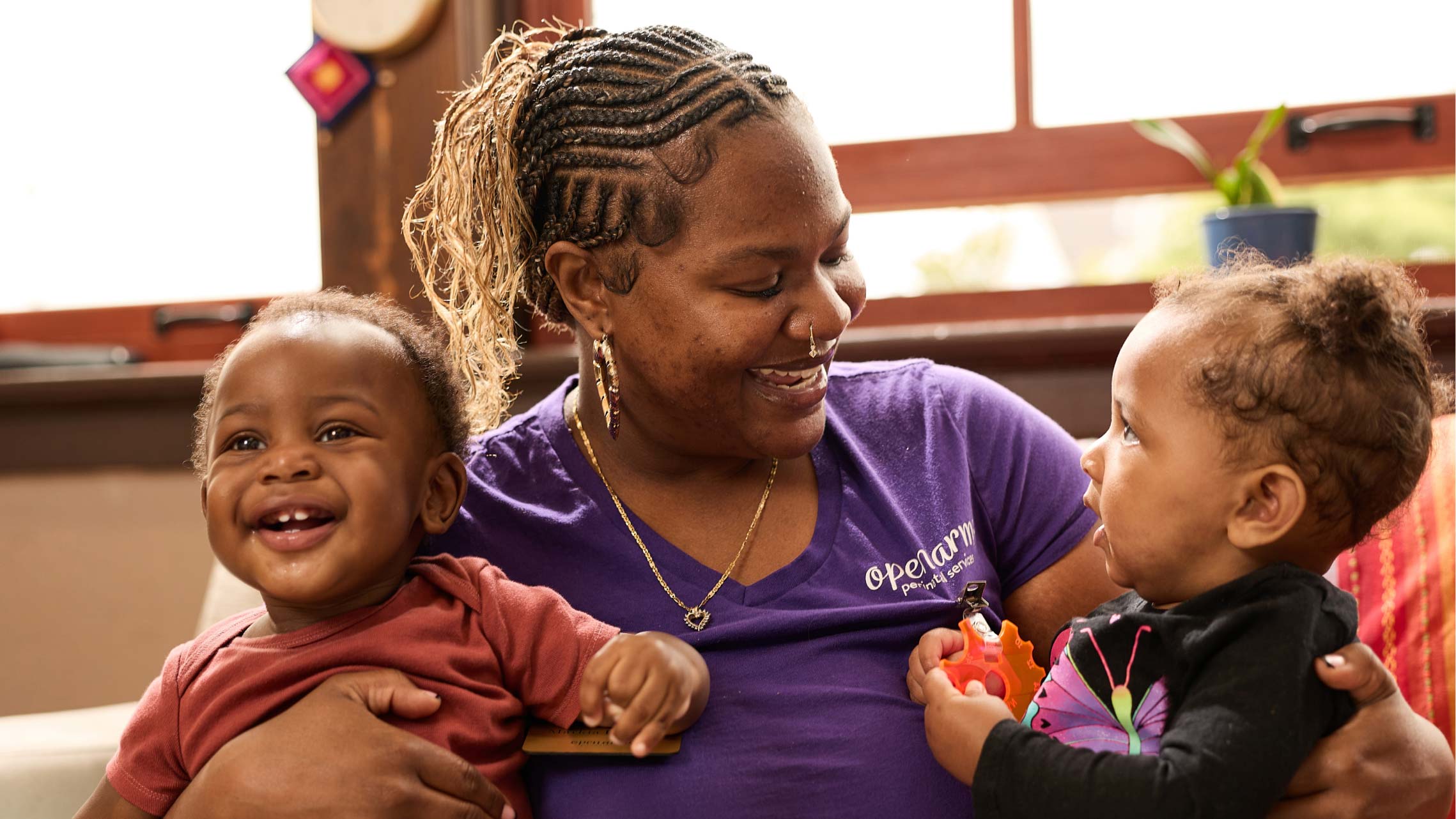 A mom smiles while holding her two babies.