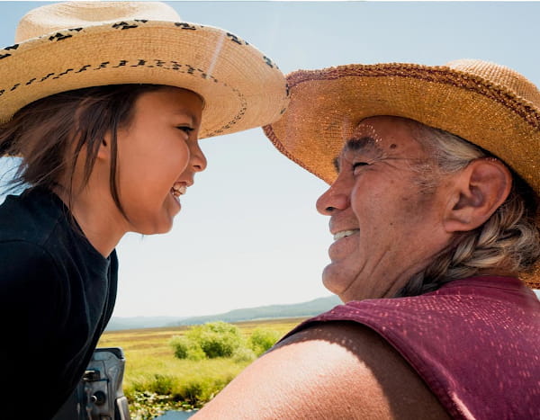 An Indigenous elder and young child smile warmly at each other.