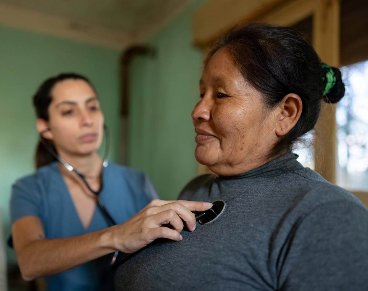 A woman has her heart checked by a nurse with a stethoscope.