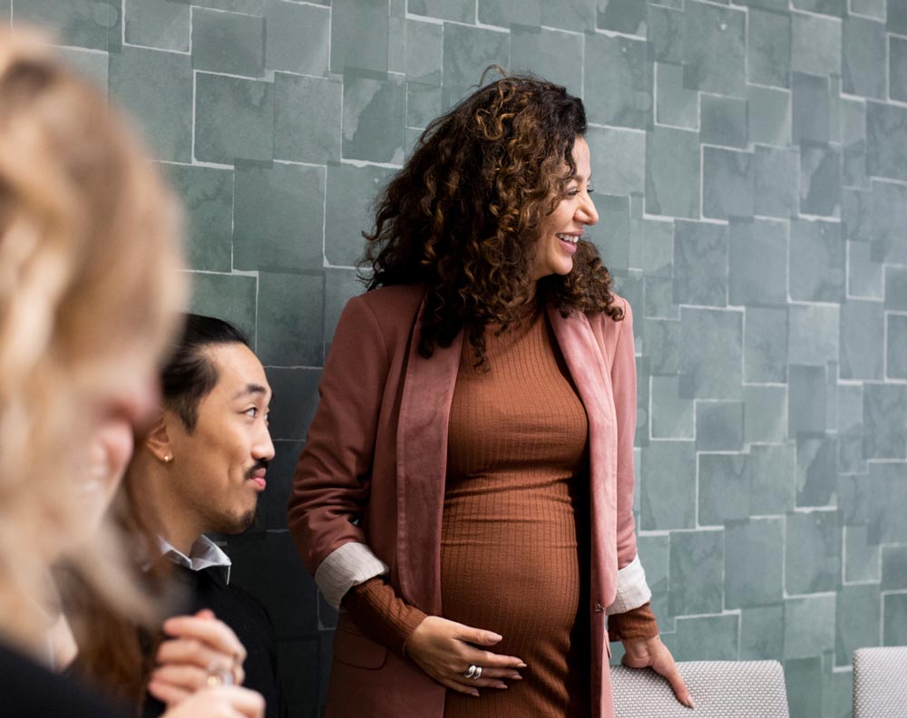 A pregnant woman leading a meeting with her coworkers in a conference room.