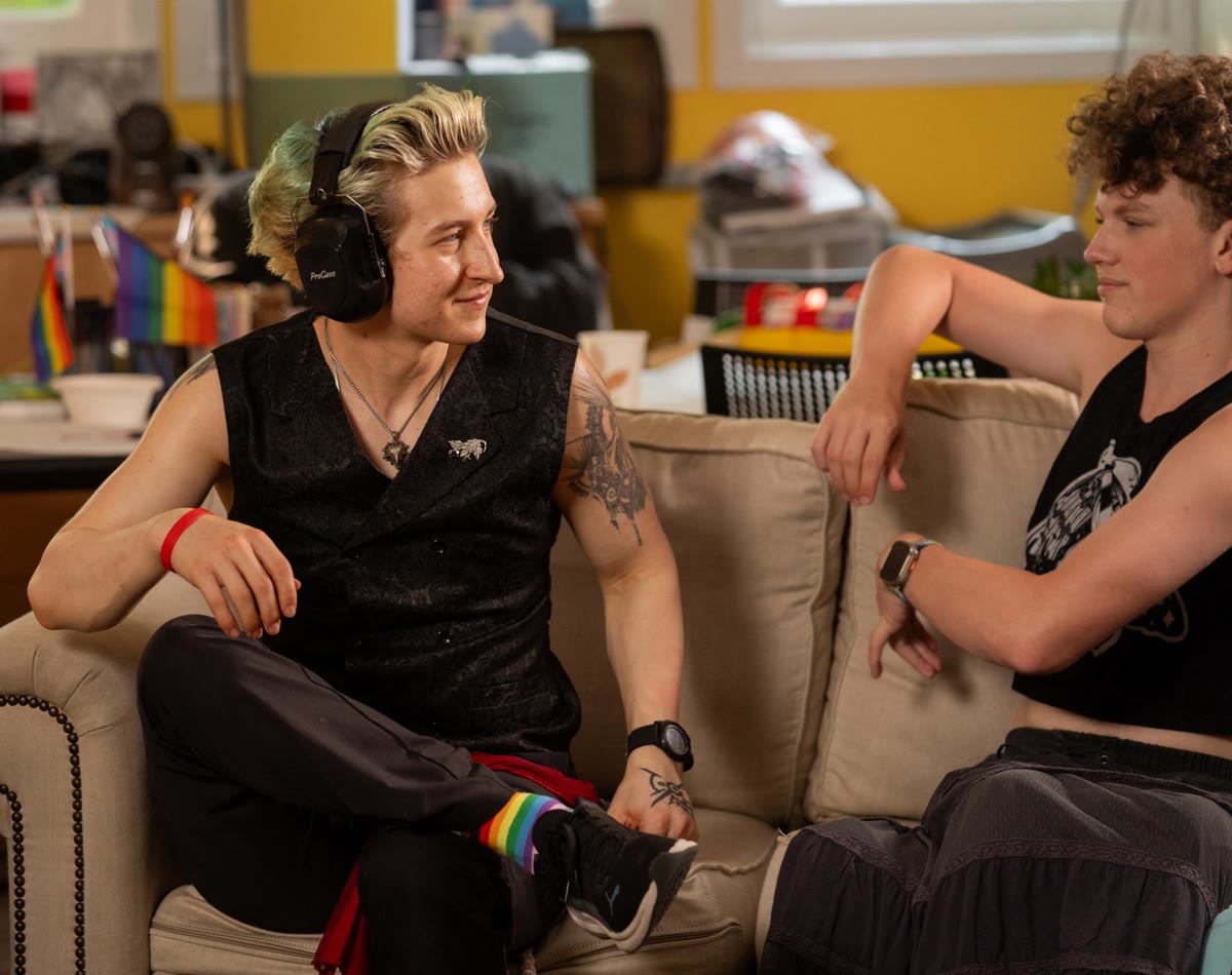 Two teenagers sit on a couch together.