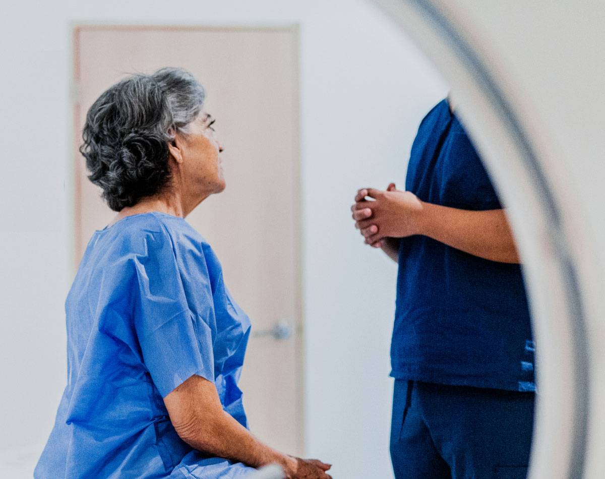 A woman sits in a medical room talking to a doctor.