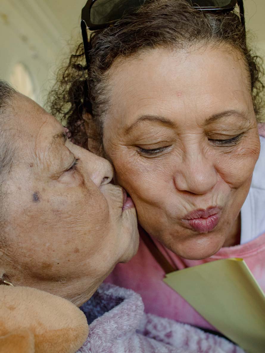 An older woman kisses her adult daughter's face.