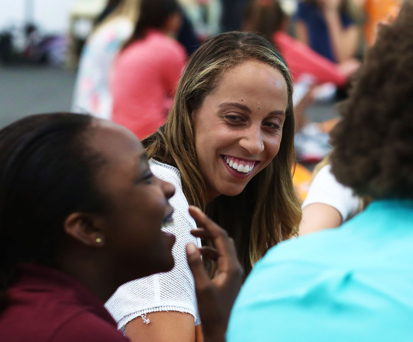 A young woman sitting and talking to a group of teenagers at an event