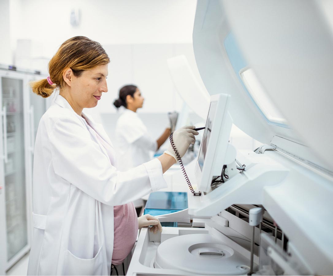 A female laboratory technician working with medical equipment.