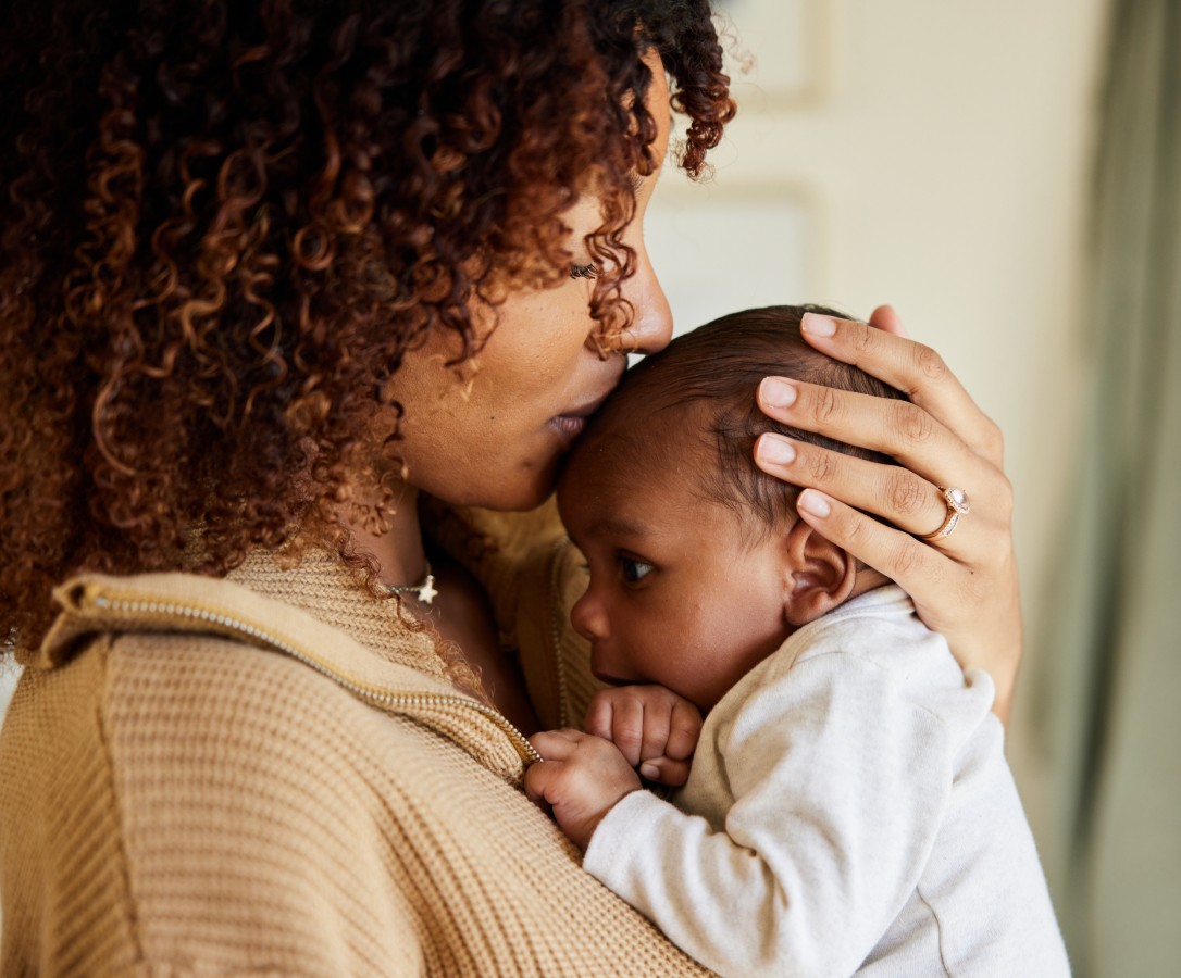 A mother cradles her baby in her arms.
