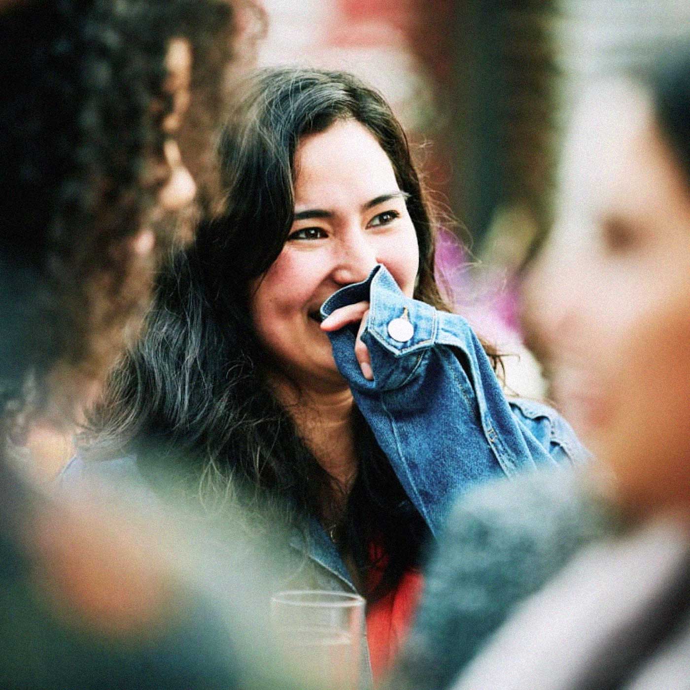 A young woman hiding her smile in a conversation.