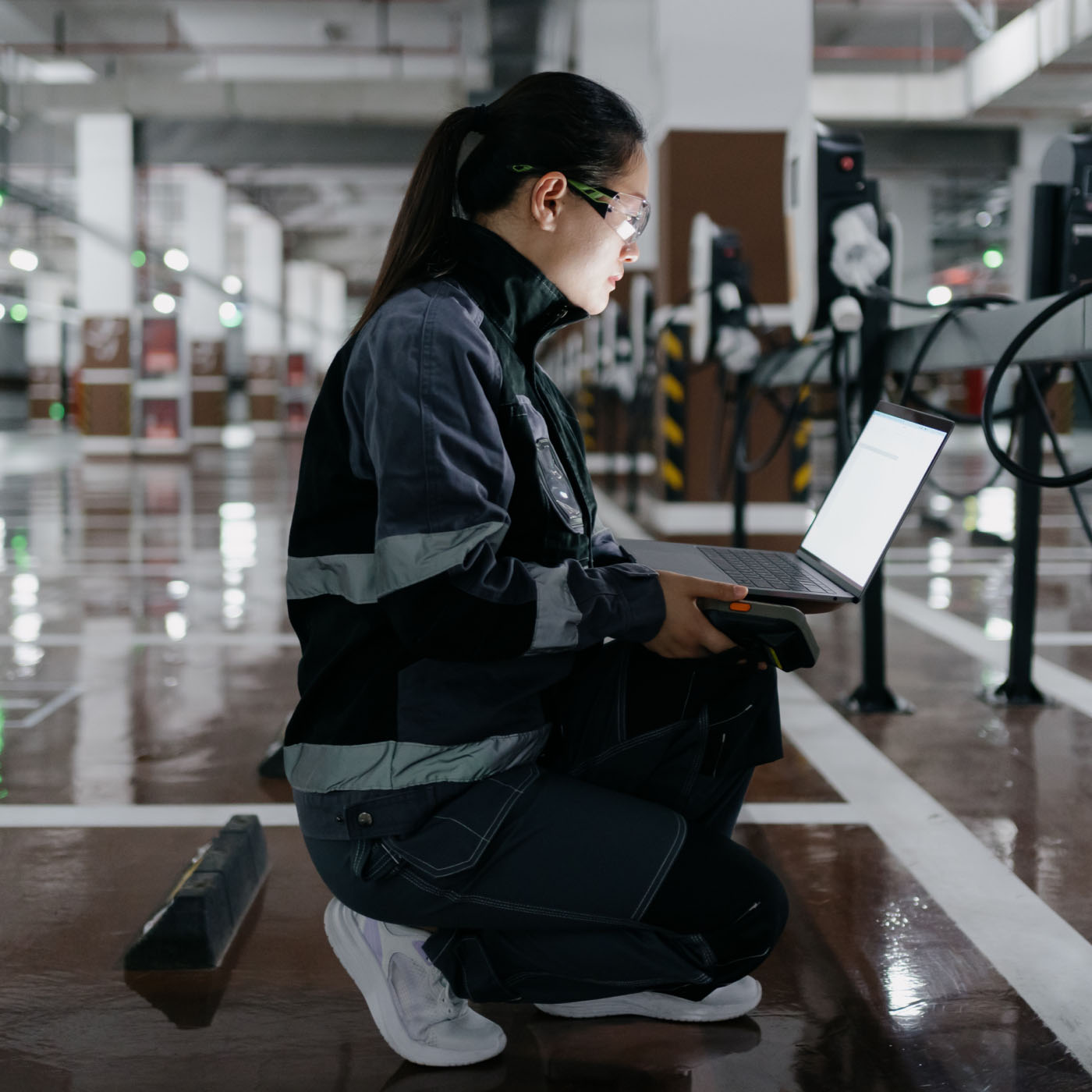 A female engineer in uniform installing a charging station in a parking lot