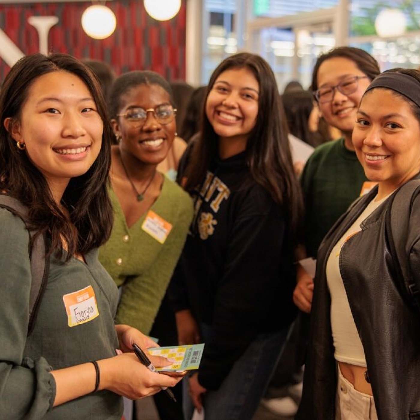 Five young women smiling for a photo at a networking event