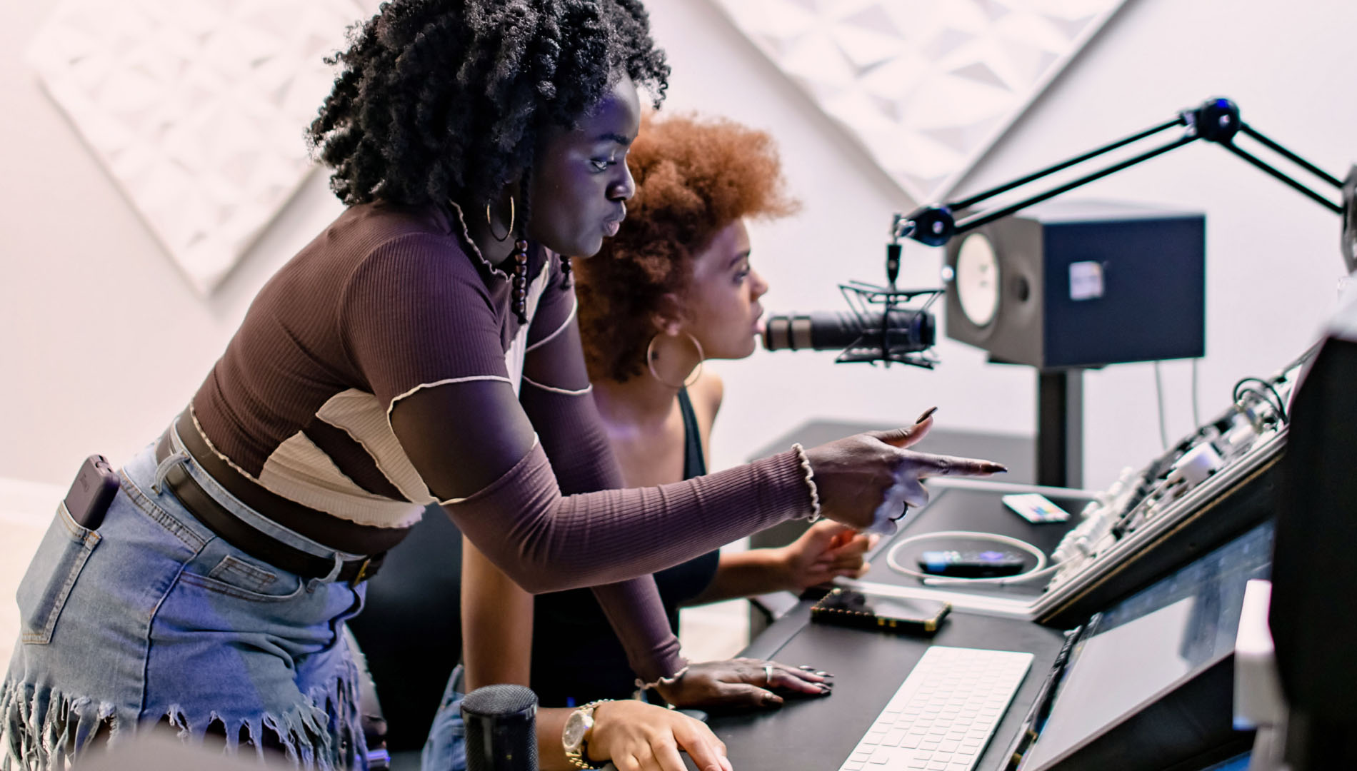 Two young teenage girls working together in a recording booth