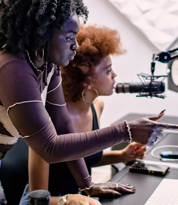 Two young teenage girls working together in a recording booth.