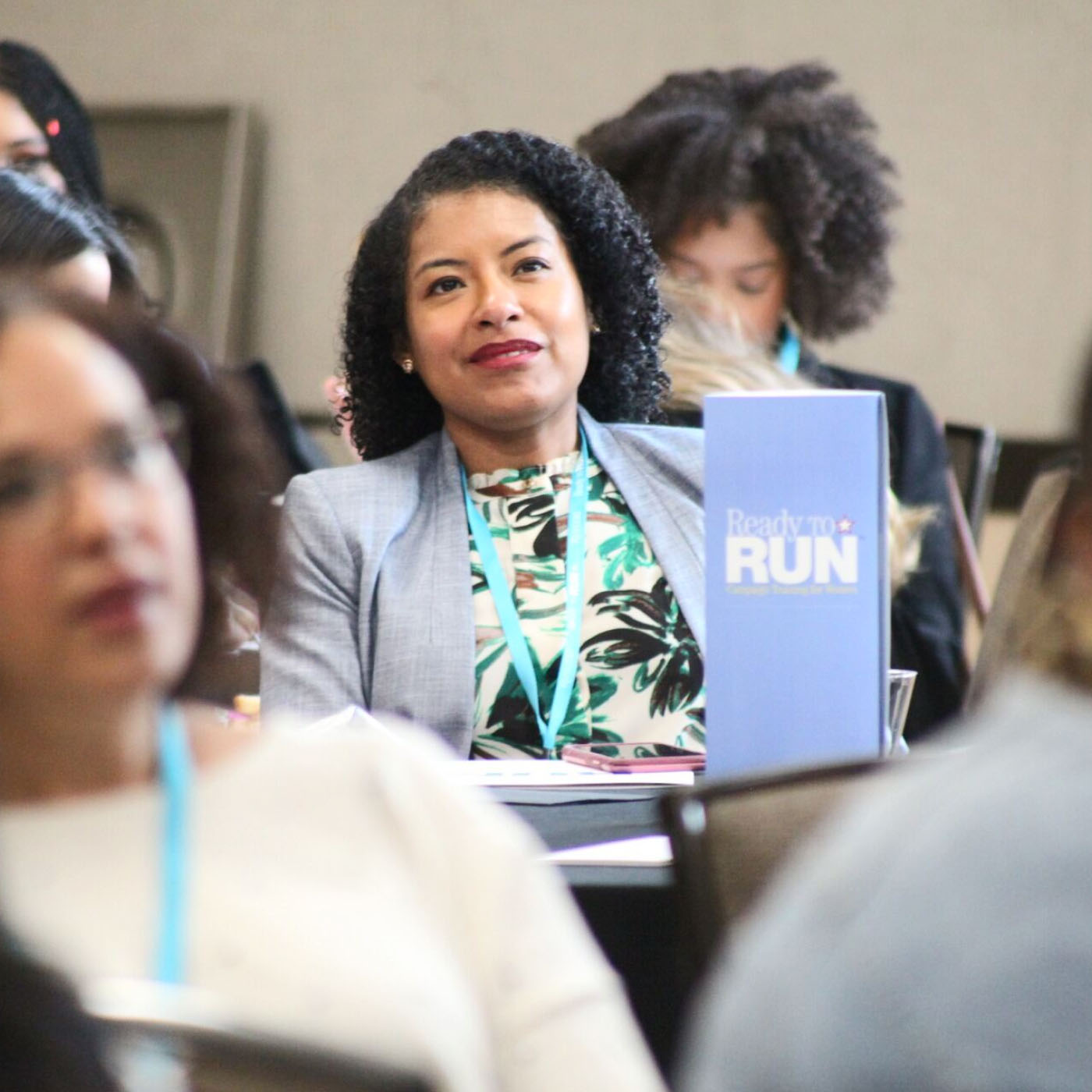 A woman smiling in the audience at a training program for electing women to public office